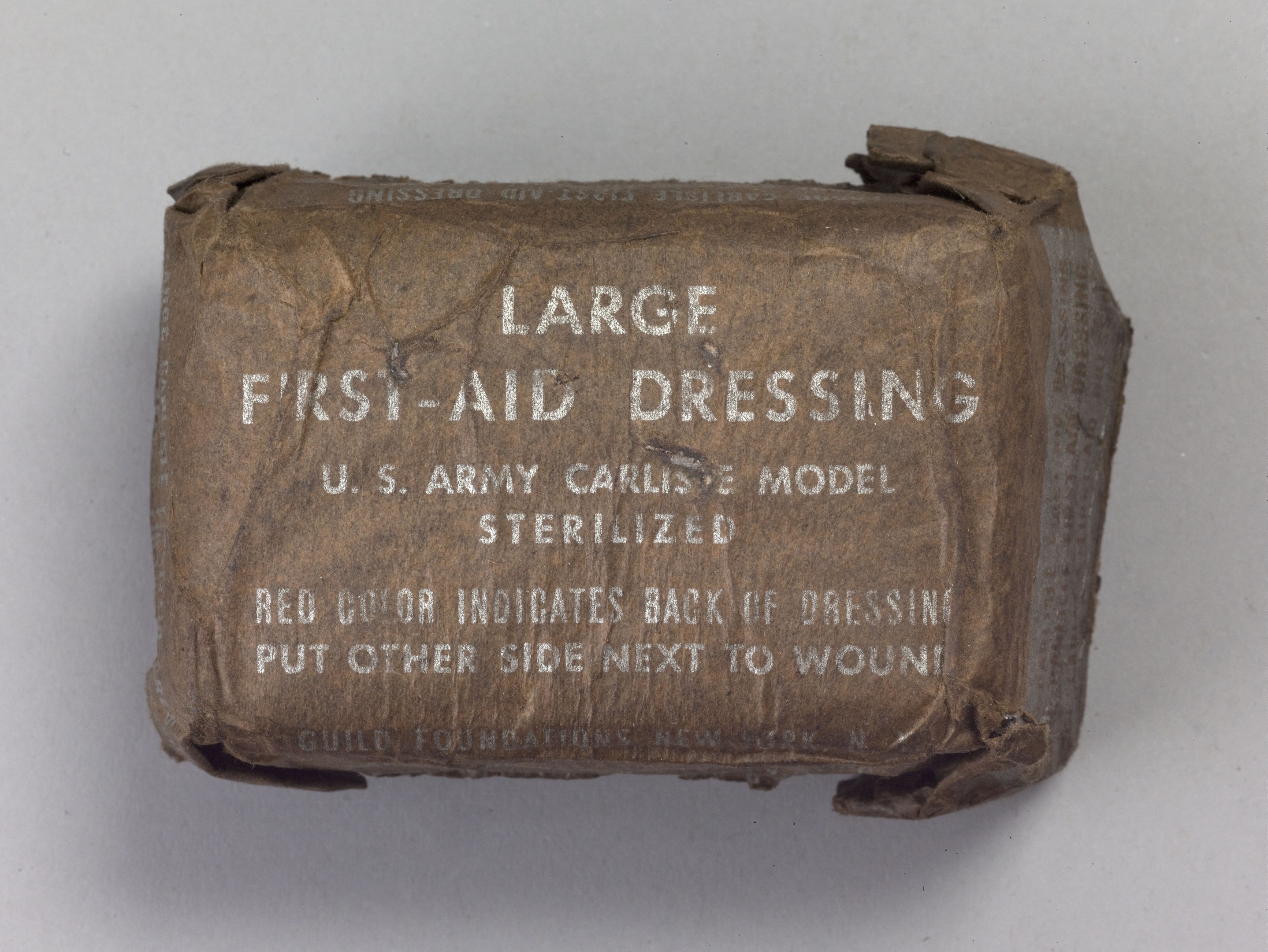 Großer rechteckiger Verbandkasten mit großer schwarzer "Großer Verbandkasten"-Aufschrift, Deckel leicht geöffnet und enthältte Inhalt auf einer weißen Oberfläche.