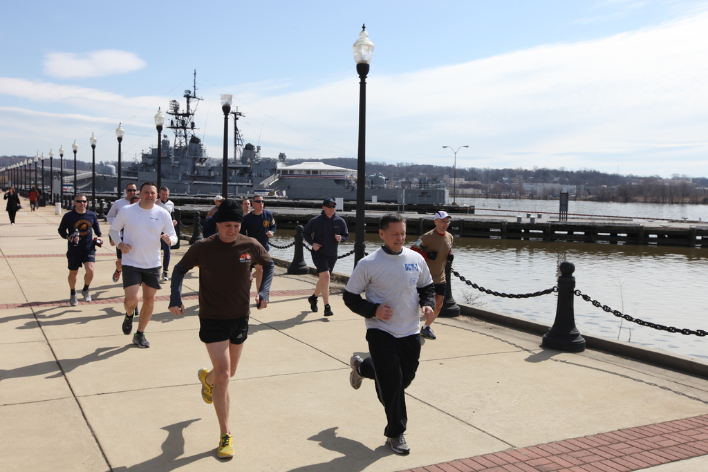 Vollst√§ndige Br√ľcke mit Menschen, die laufen, Laternenpf√§hle, Wasser, Berge und Geb√§ude im Hintergrund.