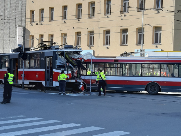 Rote und weiße Straßenbahn krachte auf die Seite der Straße mit Menschen in der Nähe und einem Gebäude im Hintergrund.
