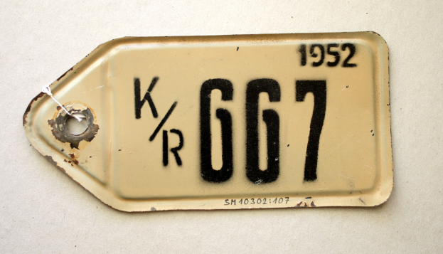 Eine weiße Flðche mit einem daran befestigten Kennzeichen, das Text und Zahlen anzeigt.