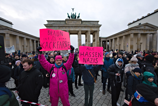 Eine Gruppe von Menschen steht vor dem Reichstagsgebäude in Berlin, Deutschland, und hält Schilder gegen die anti-nazistische Bewegung der deutschen Regierung.
