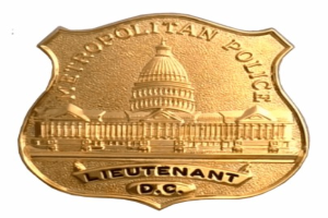 Goldenes Polizeischild mit der Inschrift "Leutnant DC" auf einem weißen Hintergrund.