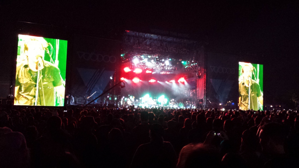 Ein Konzertbild mit einer Menge unten, einem großen Bildschirm links und einem kleineren Bildschirm rechts.