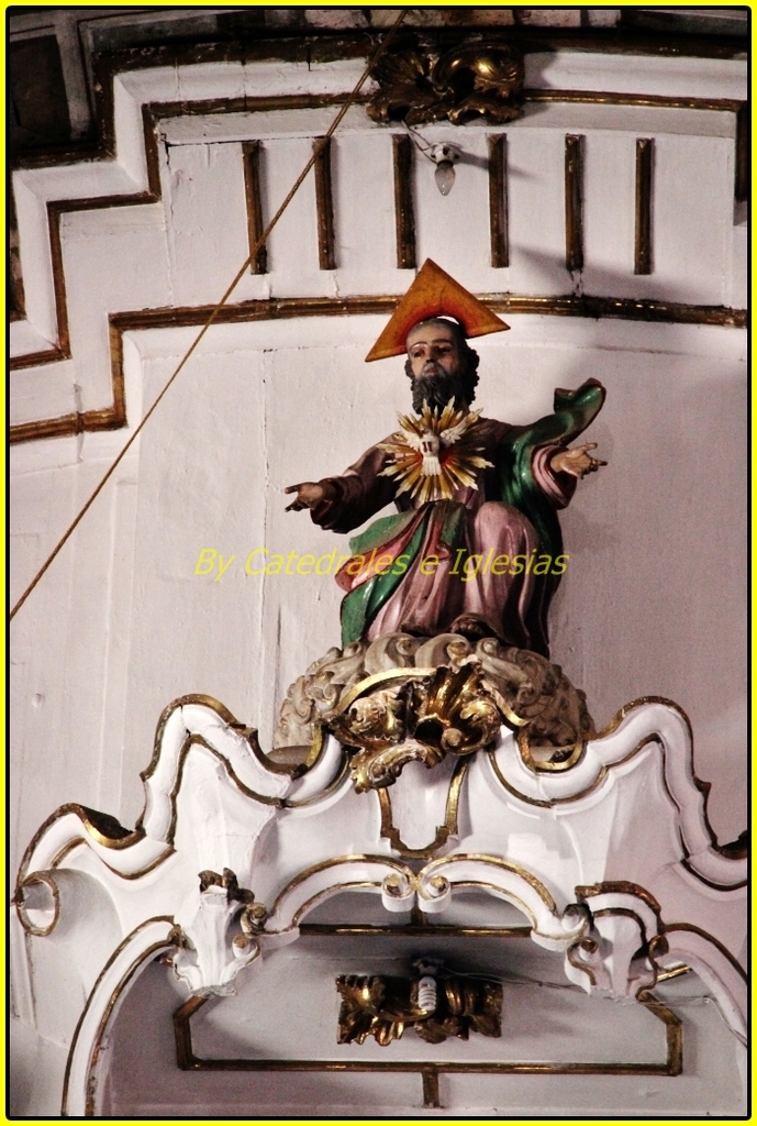 Eine Skulptur und eine Wand mit einem Kabel links und oben sowie einer Glühbirne an der Wand oben.