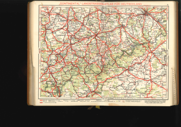 Offenes Buch mit einer detaillierten Karte von Deutschlands Straßen und Autobahnen auf einem schwarzen Hintergrund.