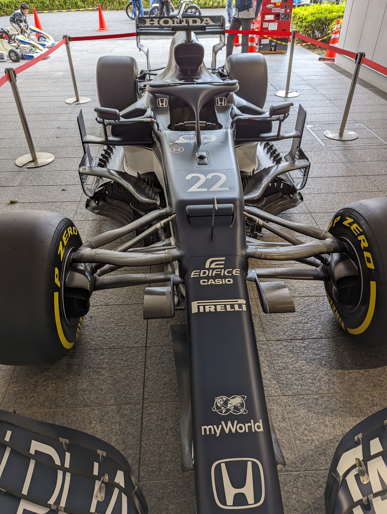 Ein McLaren Mercedes MP4-23 Formel-1-Rennwagen auf der Singapore Grand Prix, umgeben von Barrieren, Verkehrskegeln, Menschen, Fahrzeugen, Pflanzen, Bäumen und einem Gebäude im Hintergrund.