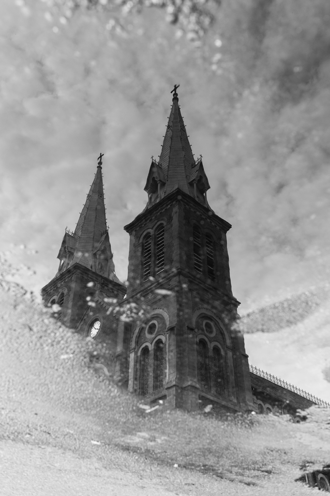 Ein Gebäude mit Wolken oben und Nebel im Vordergrund, gespiegelt auf einem Spiegel.