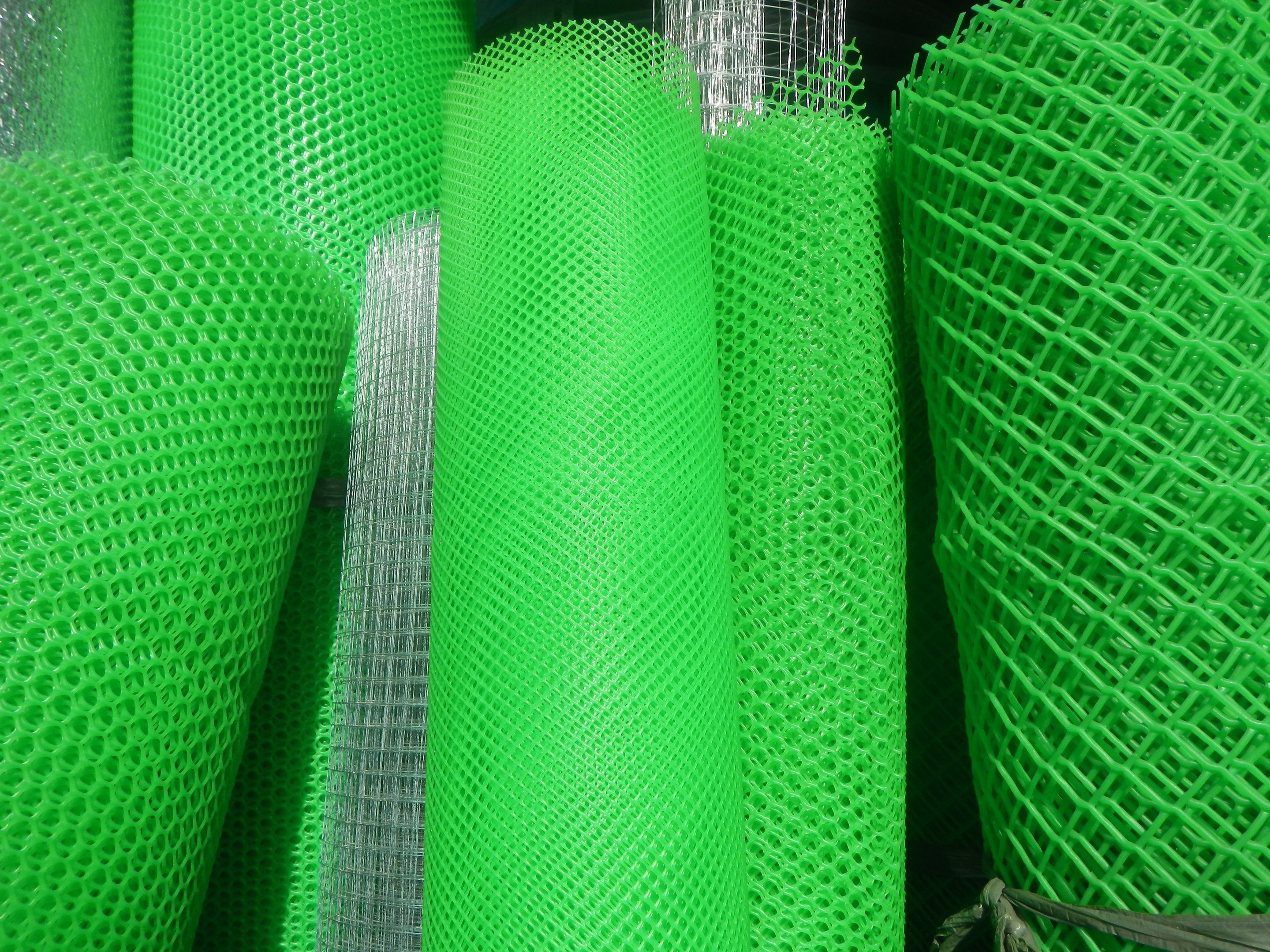 Ein Haufen grüner PVC-beschichtetes Schweißdrahtgewebe, das mit einem Seil in einem dunklen Lagerhaus gesichert ist.