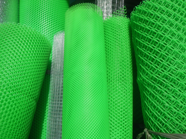 Ein Haufen grüner PVC-beschichtetes Schweißdrahtgewebe, das mit einem Seil in einem dunklen Lagerhaus gesichert ist.