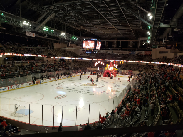 Ein Eishockeyspiel im Columbus Blue Jackets Stadion, mit Spielern auf dem Eis umgeben von einem Zaun, Zuschauern auf Sitzen und Stehplätzen und Bannern über den Boards.