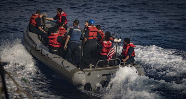 Menschen in Schwimmwesten und Helmen auf einem Boot im Wasser, mit einem Seil auf der linken Seite sichtbar.