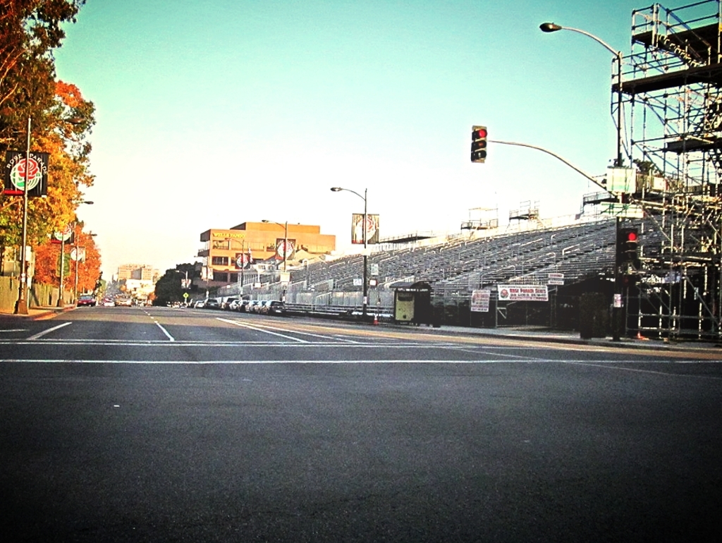 Eine Straße mit einem Verkehrszeichenmast und Gerät auf der rechten Seite, Warnschilder und mehrere Fahrzeuge vor zahlreichen Bäumen auf der linken Seite.
