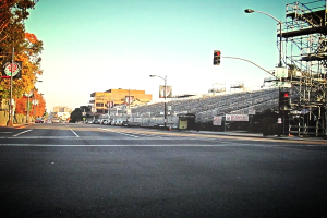 Eine Straße mit einem Verkehrszeichenmast und Gerät auf der rechten Seite, Warnschilder und mehrere Fahrzeuge vor zahlreichen Bäumen auf der linken Seite.
