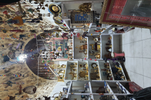 Ein vollgestelltes Souvenirshop-Interieur mit verschiedenen Artikeln in Schränken, von der Decke hängend und einem Teppich auf dem Boden.