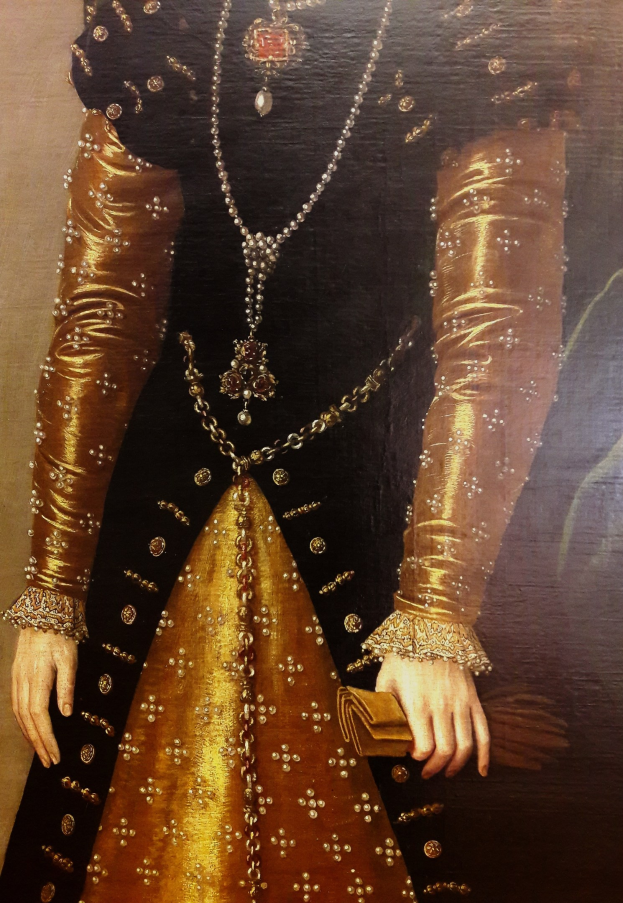 Bild einer Frau in goldnem Kleid mit hohem Ausschnitt und langen Ärmeln, die eine Tasche hält und deren Haar zu einem Knoten gebunden ist.