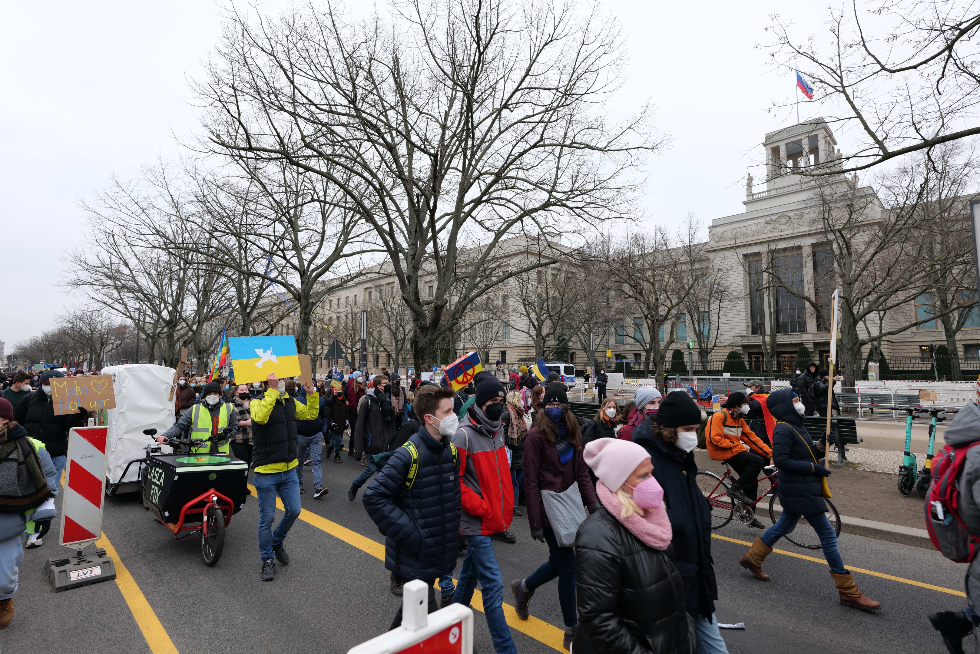 Eine große Gruppe von Menschen marschiert auf einer Demonstration in Washington, D.C. am 21. Januar 2020 mit Schildern, Bannern und Fahrrädern die Straße entlang, mit Bäumen, Schildern und einem klaren blauen Himmel im Hintergrund.