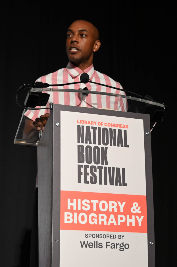 Ein Mann spricht an einem Podium mit einem Mikrofon vor einem Schild, auf dem "National Book Festival Geschichte & Biografie" steht, bei einer Abendveranstaltung.